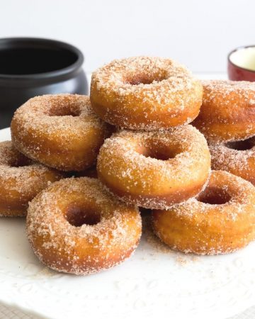 A stack of sugar donuts on a cake stand.