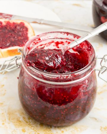 A mason jar with raspberries jam.