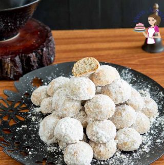 A stack of snowball cookies on a plate.