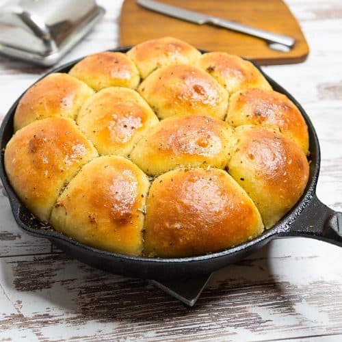 A cast iron skillet with dinner rolls.
