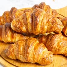 Stack of Croissants on a wooden board.