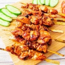 A wooden board with Asian skewers and glaze.