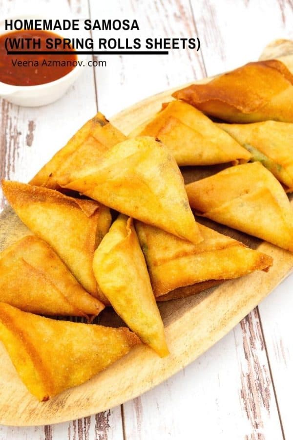 A stack of samosas on a wooden board.