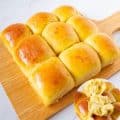 Soft dinner rolls on a wooden board.