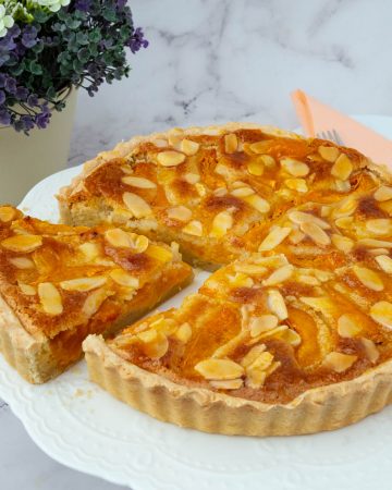 Tart with fresh apricots on a cake stand.